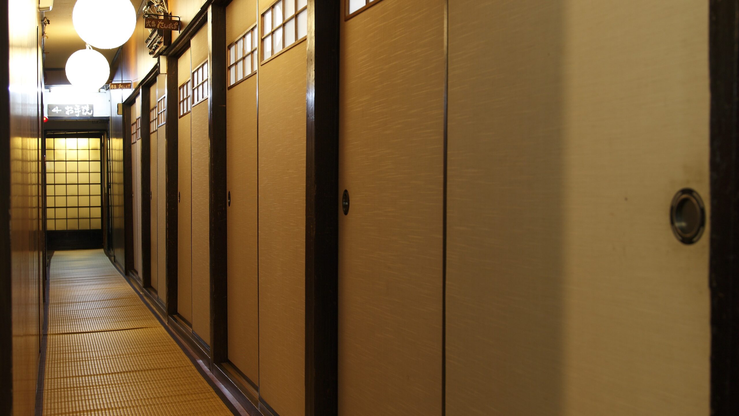 襖が並ぶ静かな廊下。やわらかな灯りの中に、しらさぎ荘の内側の時間が流れている。